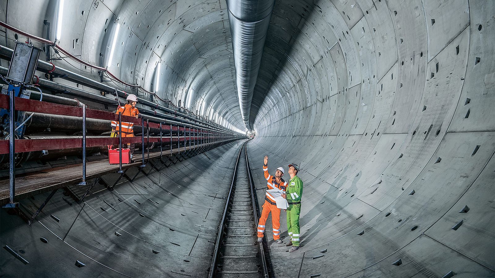 Tres obreros de la construcción discuten en el tubo de un túnel.
