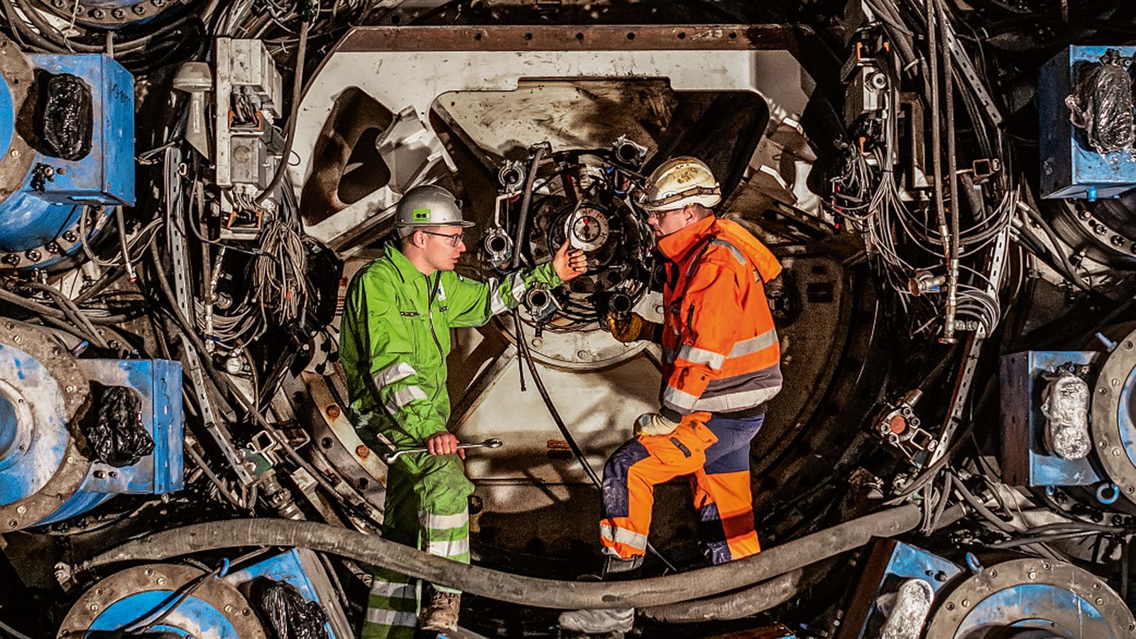 Zwei Mitarbeiter stehen vor einer Maschine und diskutieren auf einer Baustelle